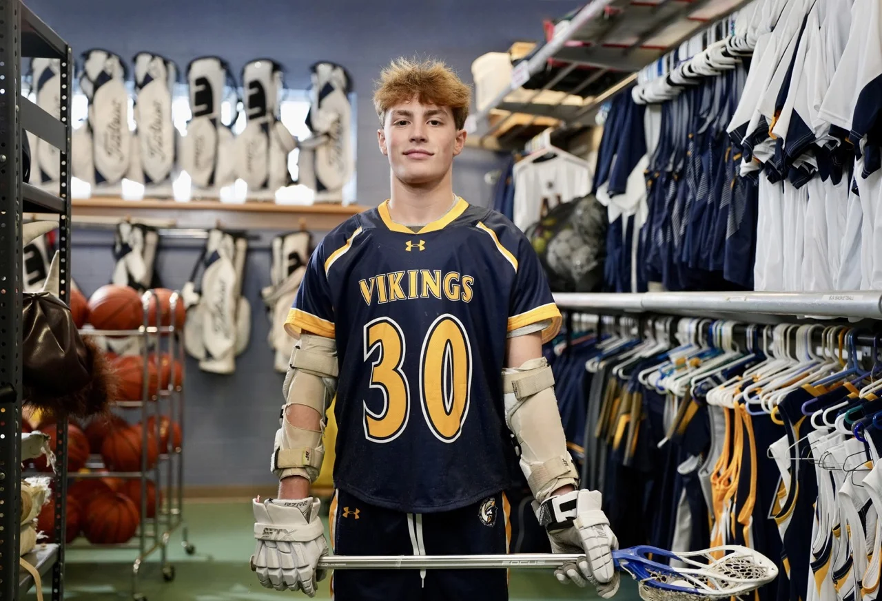 lacrosse player standing in equipment room getting geared up